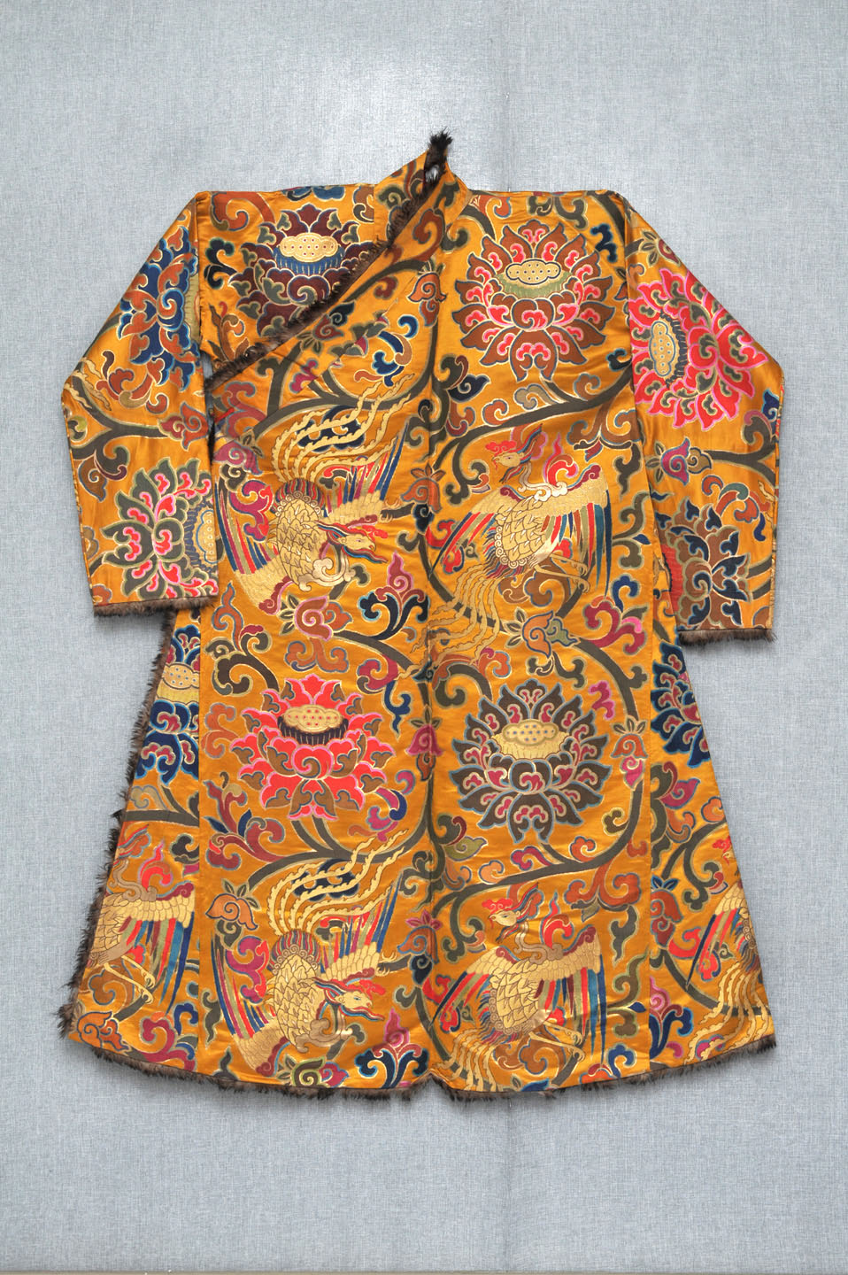 此长袍右衽斜襟,领口,衣襟边嵌皮毛为饰,整体以各色团花,勾藤花纹装饰